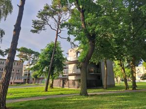 a building in the middle of a park with trees at Domek w Parku Hel in Hel