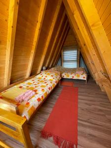 an attic bedroom with a bed and a red rug at Brvnara Beli Kamen 1 in Bešenovački Prnjavor