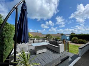 a patio with an umbrella and a couch and a table at Bungalow33 Benllech in Benllech