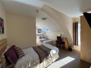 a bedroom with two beds and a desk in a room at Wingfield Hotel 