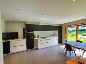 a kitchen with white and black cabinets and a table at Le Téléski du Terret; meublé de 2 à 4 personnes in Le Grand-Bornand +8 photos