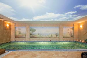 a swimming pool in a building with paintings on the wall at Amber dream Karkle in Karklė