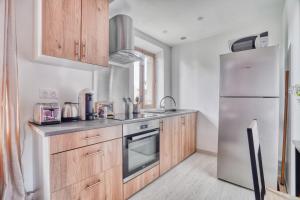 eine Küche mit Holzschränken und einem Kühlschrank aus Edelstahl in der Unterkunft Le Rubis de Gonesse •CDG•Parc Expo•Astérix in Gonesse