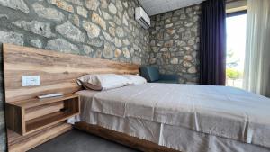 a bedroom with a bed and a stone wall at RUSTICO in Shirokë
