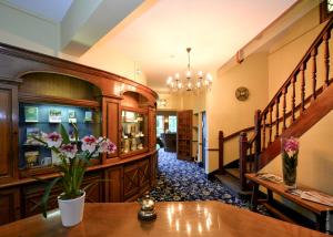 a lobby with a staircase and flowers on a table at Hostellerie Saint Pierre in Saint-Pierre-du-Vauvray