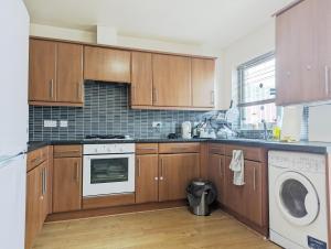 a kitchen with wooden cabinets and a washer and dryer at Guest Rooms Near City Centre & Dock Free Parking in Liverpool