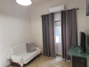 Zimmer mit einem Stuhl, einem TV und einem Fenster in der Unterkunft Yiannis Sokaki House in Rhodos (Stadt)