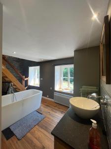ein großes Bad mit einer Badewanne und einem Waschbecken in der Unterkunft Le repaire des amoureux in La-Roche-en-Ardenne