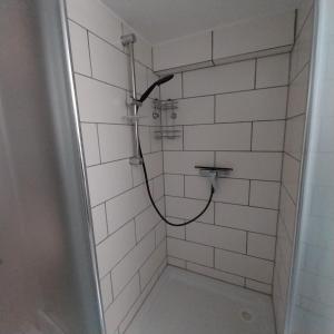 ein Bad mit einer Dusche und weißen Fliesen in der Unterkunft Souterrainwohnung in Gottmadingen