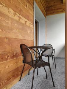 two chairs and a table in front of a wooden wall at BAITA LARIX BORMIO in Bormio