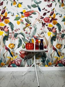 a wall with a floral wallpaper with fruits and vases on a table at Chez Hélène Luxury BNB in Maastricht