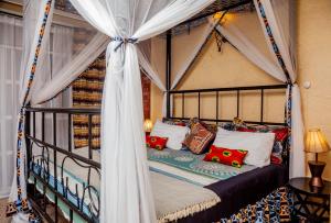 um quarto com uma cama de dossel e almofadas em Jet Villas Entebbe ( JVE ) em Entebbe