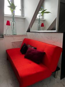 a red couch in a room with two windows at Chez Hélène Luxury BNB in Maastricht