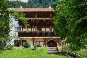 ein großes Haus mit Blumenkästen auf den Balkonen in der Unterkunft Alpenhotel Sonneck - mit Bergbahnticket in Bad Hindelang