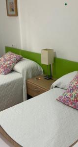 a bedroom with two beds and a table with a lamp at Apartamentos Alcañiz, Alicia in Alcañiz