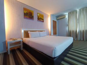 a bedroom with a large white bed and a table at First Residence Hotel by RVH in Cukai