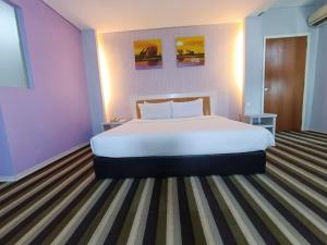 a bedroom with a large bed in a purple room at First Residence Hotel by RVH in Cukai