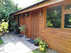 a wooden cabin with potted plants next to a door at Manor Garden Lodge in Wirral