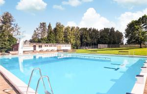 a large blue swimming pool with a field in the background at Lovely Home In Lvestad With House A Panoramic View in Lövestad