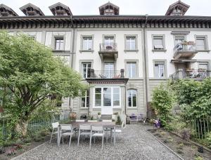 a large white building with a table and chairs at Am Pavillon, Bed&Kitchen in Bern