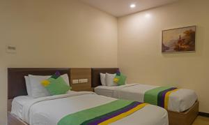 ヴィシャカパトナムにあるTreebo Trend Seasons Comfortのベッド2台が備わる客室で、壁には絵画が飾られています。
