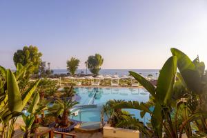 einen Pool mit Stühlen und das Meer im Hintergrund in der Unterkunft Capo Bay Hotel in Protaras