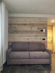 a couch in a room with a wooden wall at BAITA LARIX BORMIO in Bormio