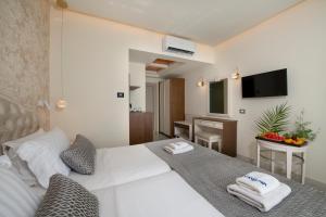 una camera da letto con un letto bianco e asciugamani di Vantaris Luxury Beach Resort a Georgioupolis