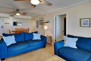 sala de estar con 2 sofás azules y comedor en Regency Towers 802 East, en Pensacola Beach