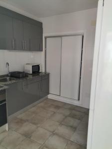una cocina con armarios grises y una puerta corredera de cristal en Apartamentos La Encarnación I, en Los Alcázares