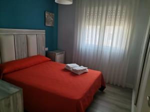 1 dormitorio con cama roja y ventana en Apartamentos La Encarnación I, en Los Alcázares