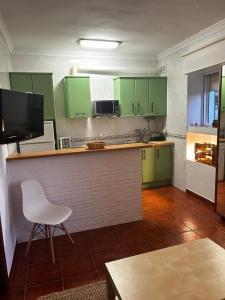 una cocina con armarios verdes y una silla blanca en Apartamento ¨El lizón¨, en Setenil