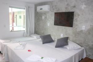 a room with two beds with white sheets and a window at Porto Center Hotel in Porto Seguro