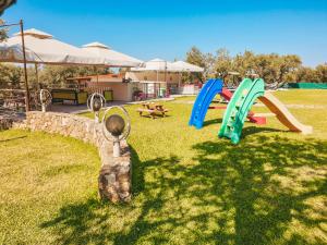 a playground with slides and a stone wall at Aroma Studios and Apartments in Vourvourou