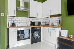cocina con armarios blancos y lavadora en Hidden retreat in the heart of the city - 2 Bed Apt en Nottingham