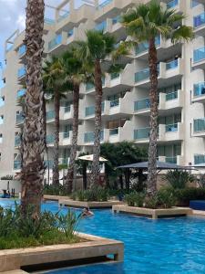 uma piscina com palmeiras e um edifício em Apartament amb vistes al mar! em Salou