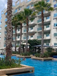 een zwembad met palmbomen en een gebouw bij Apartament familiar amb vistes al mar! in Salou