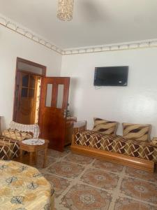 a living room with a couch and a tv on the wall at Beach House in Asilah