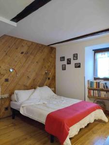 1 dormitorio con 1 cama con pared de madera en Chez Jules, en Saint-Martin-Vésubie