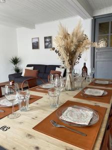 einem Holztisch mit Tellern und Gläsern darauf in der Unterkunft Maison Opaline in Berck-sur-Mer