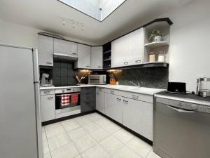 a large kitchen with white cabinets and appliances at Maison Opaline in Berck-sur-Mer +10 photos