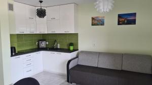 uma cozinha com armários brancos e um sofá num quarto em Comfy Studio em Rzeszów