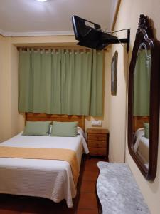 een slaapkamer met een bed, een spiegel en een tv bij Hostal Infantes in Toledo