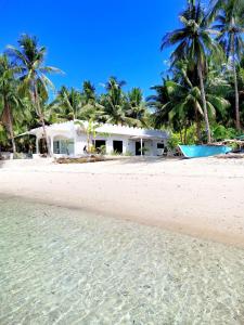 a white house on a beach with palm trees at BEACH FRONT WHITE HOUSE VILLA in Maria