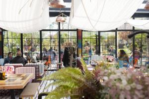 personas sentadas en mesas en un restaurante con ventanas en Sandalandala en Vama Veche