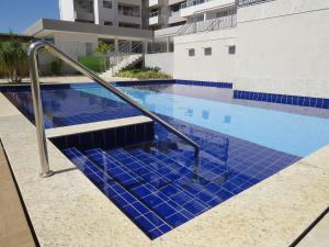 una piscina con azulejos azules en un edificio en Recanto do Bosque Apartamentos para Temporada en Caldas Novas