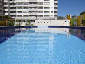 a large swimming pool in front of a building at Recanto do Bosque Apartamentos para Temporada in Caldas Novas