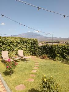 a garden with two chairs and a table and flowers at Good Morning Etna in Bronte