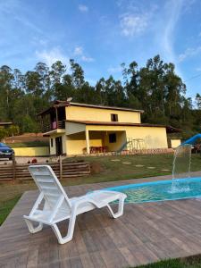 uma cadeira branca sentada num deque ao lado de uma piscina em Sitio recanto Feliz em Mariana