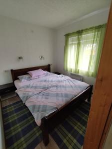 a bedroom with a bed with pink sheets and a window at Duke in Žabljak